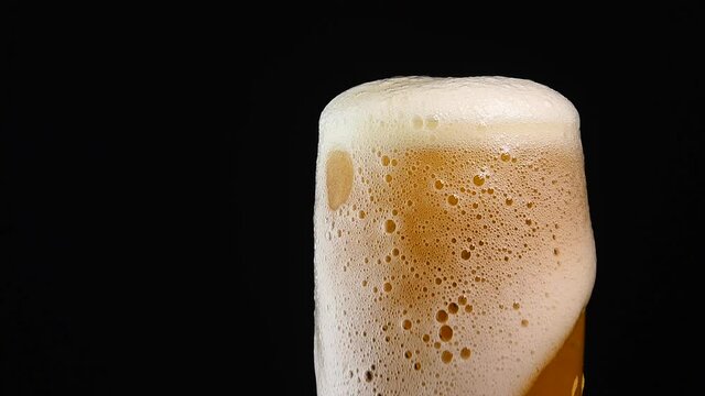 Close up pouring lager beer in glass over black
