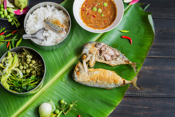 Fried mackerel with shrimp paste sauce and vegetable set. Thai food on a black wooden table