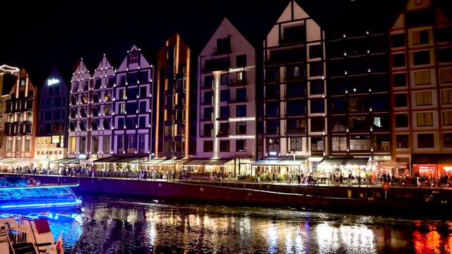 Night view pan shot of Polish architecture next to motlawa river and people enjoying their time over a weekend