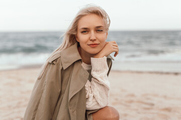 Young woman sitting on beach in windy weather