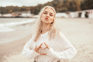 Fototapeta na wymiar Carefree woman gesturing heart on beach