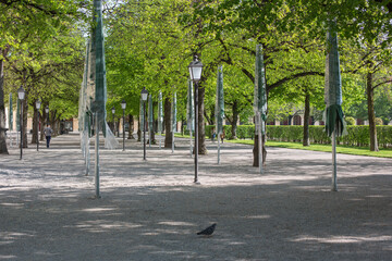 München: Spaziergang durch den idyllischen und leeren Hofgarten mit blühenden Linden Bäumen während der Corona Virus Pandemie nahe einem Café mit geschlossener Terrasse  