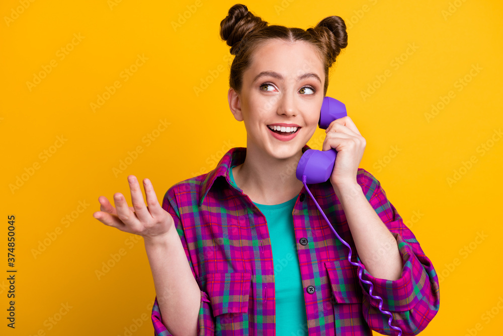 Sticker Photo of charming lady two funny buns hold cable telephone handset speaking chatting friends discussing fresh gossips rumors wear casual plaid shirt isolated yellow bright color background