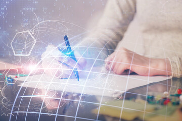 Multi exposure of hands making notes with world map hologram and data theme icons. Concept of global computer data.