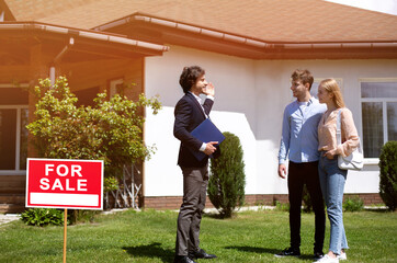 House agent showing new property to potential buyers, outside. Blank space