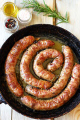 Selective focus. Fried homemade sausages in a frying pan on a wooden table. Rustic style.