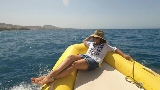 One young woman lying down on a boat or dinghy smiling and enjoying summer vacations in the middle of the sea traveling and discovering in boat 
