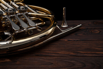 Musical instrument, French horn on a wooden surface on a black background