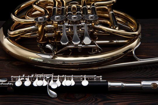 Two musical instruments French horn and flute on a wooden surface on a black background