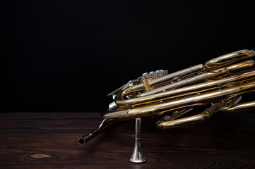 Musical instrument, French horn on a wooden surface on a black background