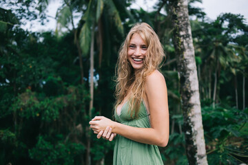 Woman in fashionable green dress laughing at rainforest