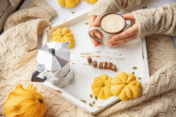 Autumn mood, warm cup of hot coffee warming in hands of woman by window