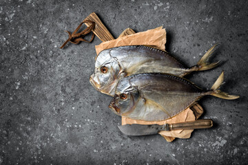 Two whole salty vomer fish on wooden board with vintage knife