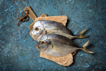 Two whole salty vomer fish on wooden board