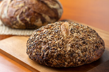 An artisan bread loaf with seeds on wooden background