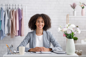 Smiling young stylist or fashion designer. Woman with notepad in workplace