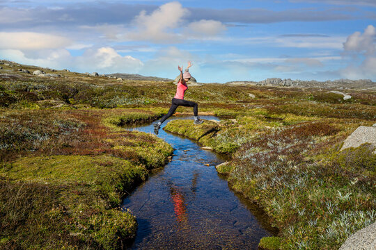 Woman run free jumping little meandering stream in high country