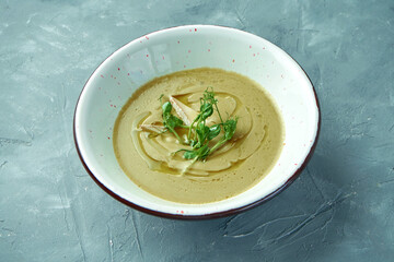 Creamy broccoli soup with camembert cheese, microgreen and olive oil in a white bowl