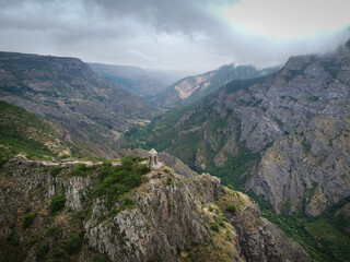 Aerial Drone view of Small chapel in the top of the mountain, surrounded by high mountain range, tourists walks around