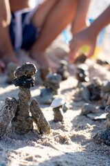 On a sunny summer day, children build figures from stones in the sand.