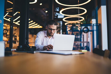 Serious businessman working on laptop in modern workspace