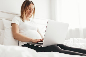 Naklejka premium Pregnant freelancer using laptop on bed