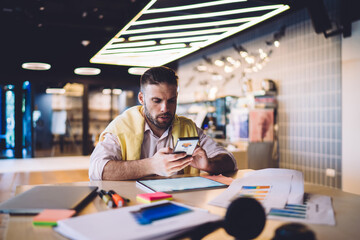 Obraz premium Businessman checking message on phone while sitting in cafe