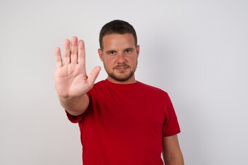 Young handsome caucasian man isolated over white background doing stop gesture with palm of the hand. Warning expression with negative and serious gesture on the face