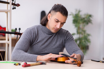 Young male repairman repairing violin