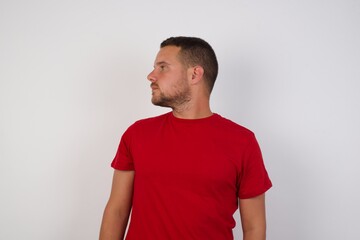 Close up side profile photo Young handsome Cucasian man wearing red shirt standing against white background ready to have a walk.