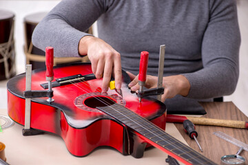 Young male repairman repairing guitar