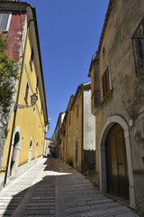 Fototapeta na wymiar A narrow street among the old houses of Santa Croce del Sannio, a medieval village in the Campania region. 