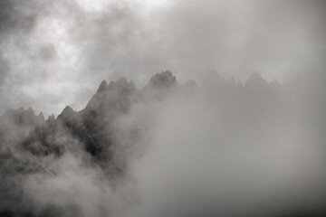 Fototapeta na wymiar Mountain peaks shrouded by fog and low clouds