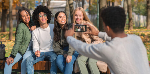 Black guy taking photo of his friends, using smartphone