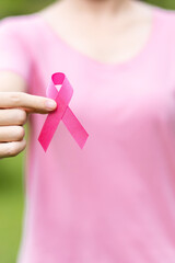 October Breast Cancer Awareness month, adult Woman in pink T- shirt with hand holding Pink Ribbon...