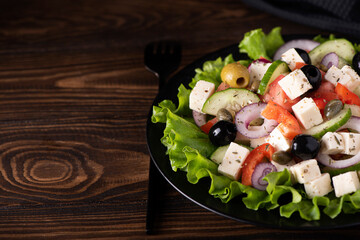 greek salad with olives and capers on a black plate