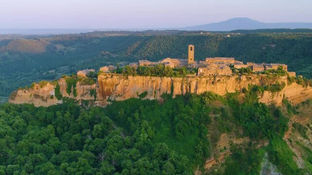 Aerial footage of medieval city on the rock,  Civita di Bagnoregio  illuminated by setting sun. Italy. 