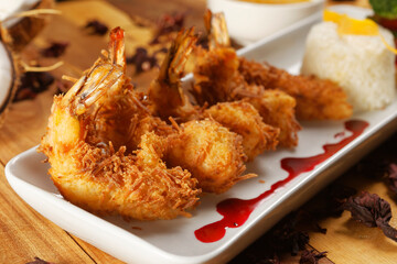 Breaded shrimp with Coconut shell in Jamaican sauce, accompanied by steamed rice and garnished with...