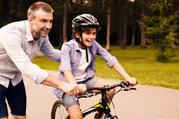 Boy learning to ride bicycle with his dad