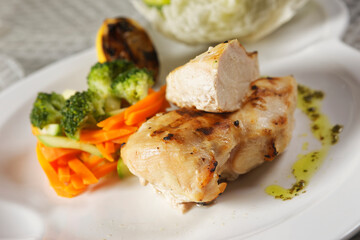 Roasted chicken breast served with a lettuce salad garnished with broccoli, carrot, pumpkin, and lemon juice.