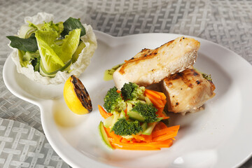 Roasted chicken breast served with a lettuce salad garnished with broccoli, carrot, pumpkin, and lemon juice.
