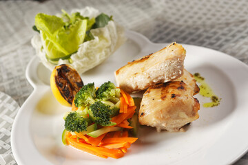 Roasted chicken breast served with a lettuce salad garnished with broccoli, carrot, pumpkin, and lemon juice.