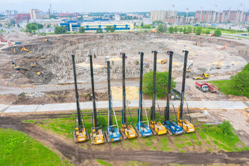 Heavy equipment for installing piles in the ground, heavy machines for driving foundation pillars are lined up. Construction aerial view from height.