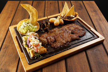 Grilled roast beef with golden chicken tacos, guacamole, chambray onions, and refried beans