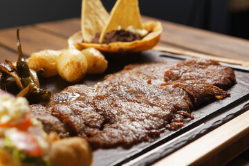 Grilled roast beef with golden chicken tacos, guacamole, chambray onions, and refried beans