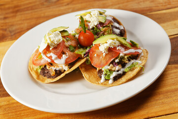 Chicken tostadas with beans, lettuce, tomato, fresh cheese and avocado.