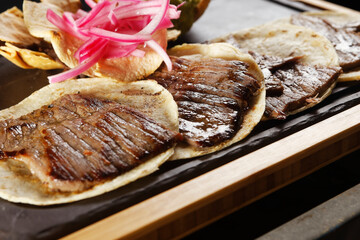 Grilled four tacos of sirloin steak served on comal with fire and accompanied by guacamole.