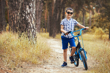 Happy kid cyclist rides in the forest on a bike.