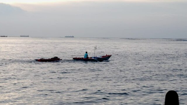 small fishing boat of local people moving in the sea with wave behind.