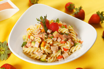 Fusilli pasta salad with ham, pumpkin, papaya, strawberry and broccoli.